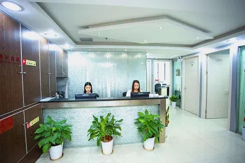 Office reception area with counters, staff, and potted plants in hallway
