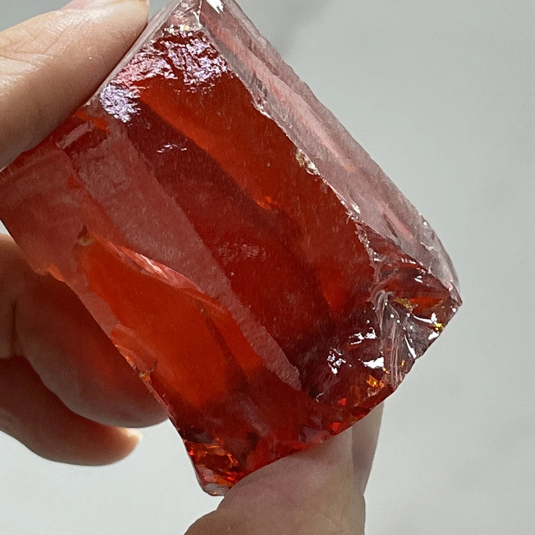 Loose red rough cubic zirconia crystal, uncut faceted side view held