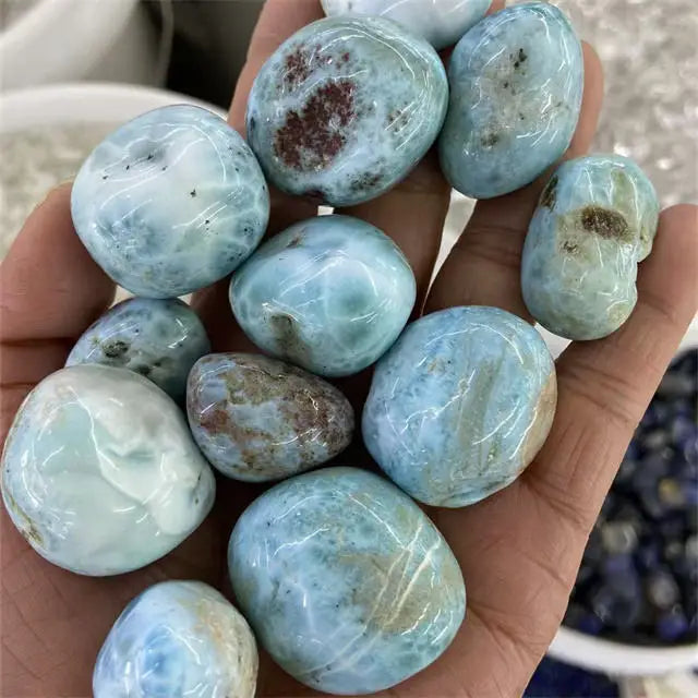 Light blue tumbled larimar stones with varied veining and cloudy white patches