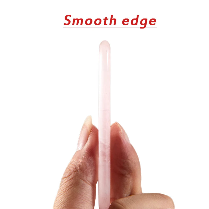 A hand holds a smooth, pale pink rose quartz Gua Sha tool showing its rounded edge against a white background.