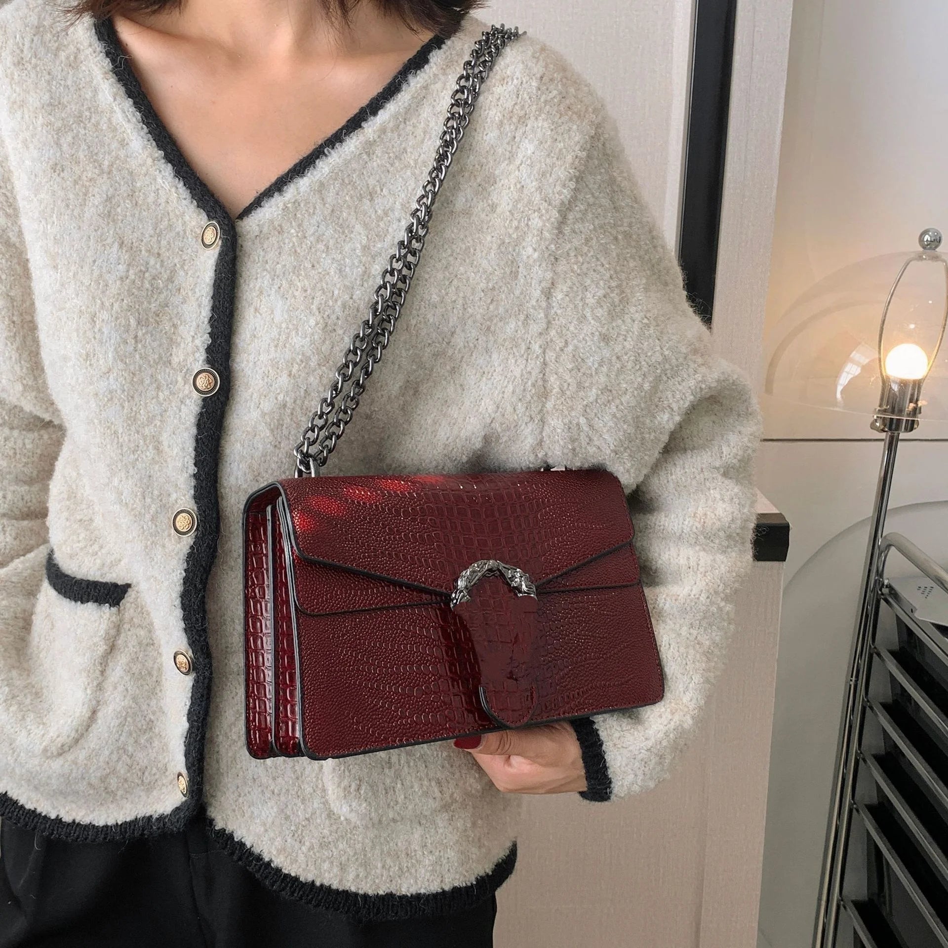 Luxury burgundy crocodile-pattern crossbody trunk bag with silver chain strap and metallic animal head clasp closure.