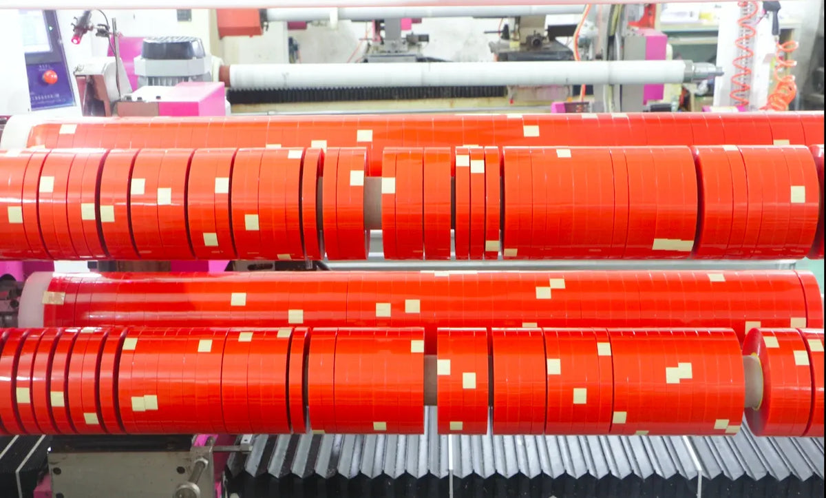 Red double-sided tape reels lined up on an industrial dispensing setup