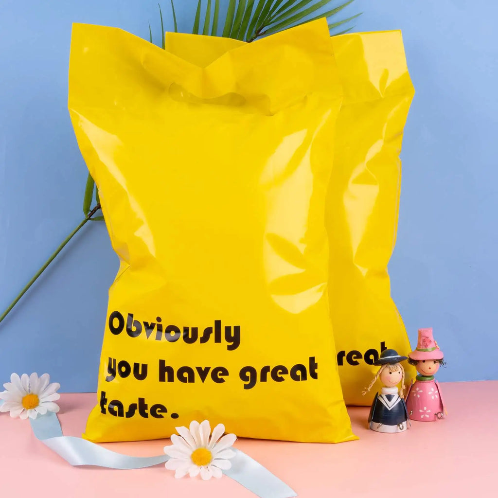 Yellow poly mailer with handle and black slogan print, shown with small decor
