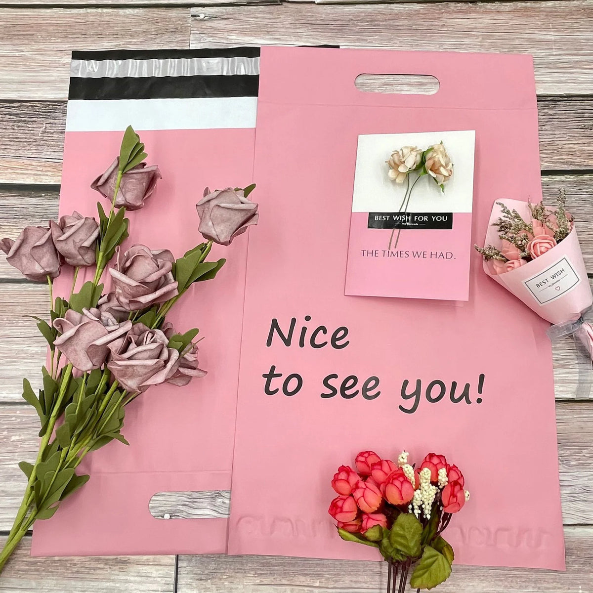 Pink plastic poly mailer with handle cutouts, floral pouch design, and “Nice to see you!” text