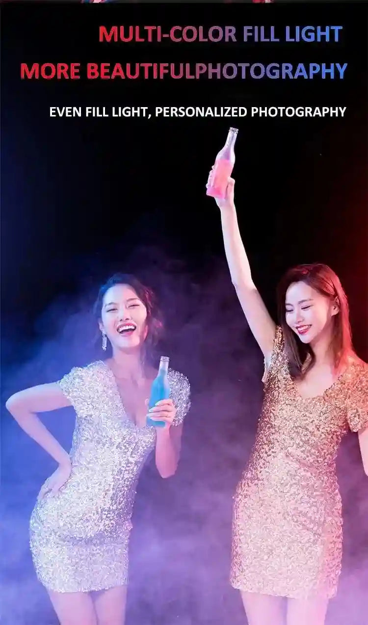 Two women in sequined dresses pose with colorful drinks under pink and blue moody lighting for portrait photography.