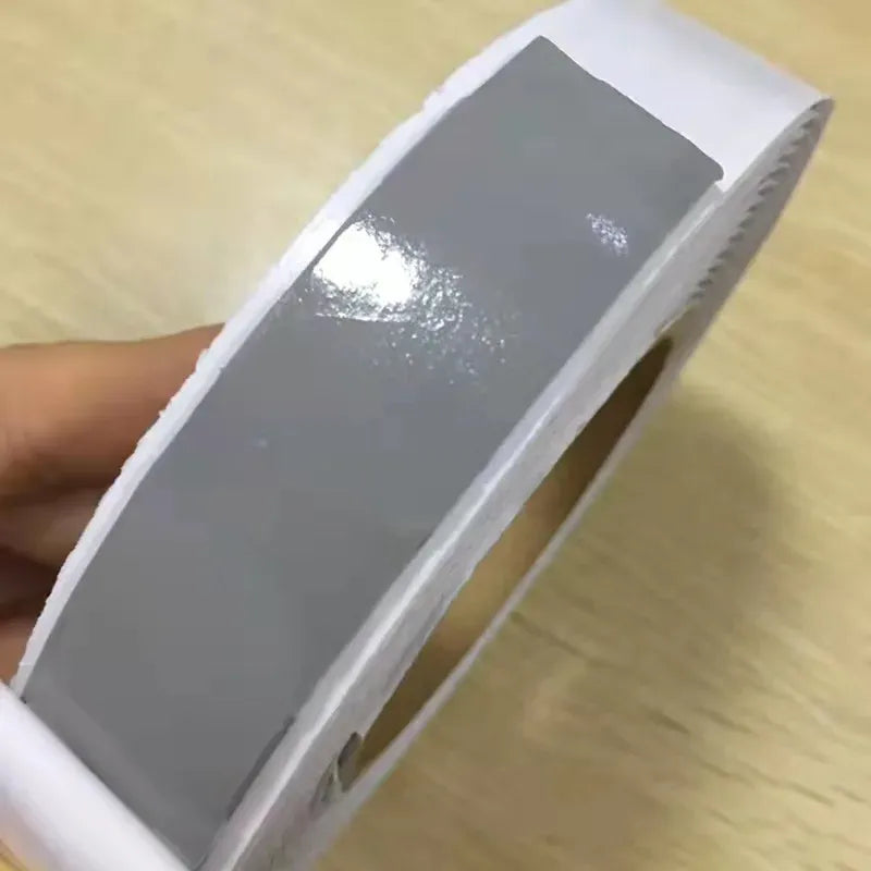 Gray foil-backed sealant strip with adhesive edge on paper liner
