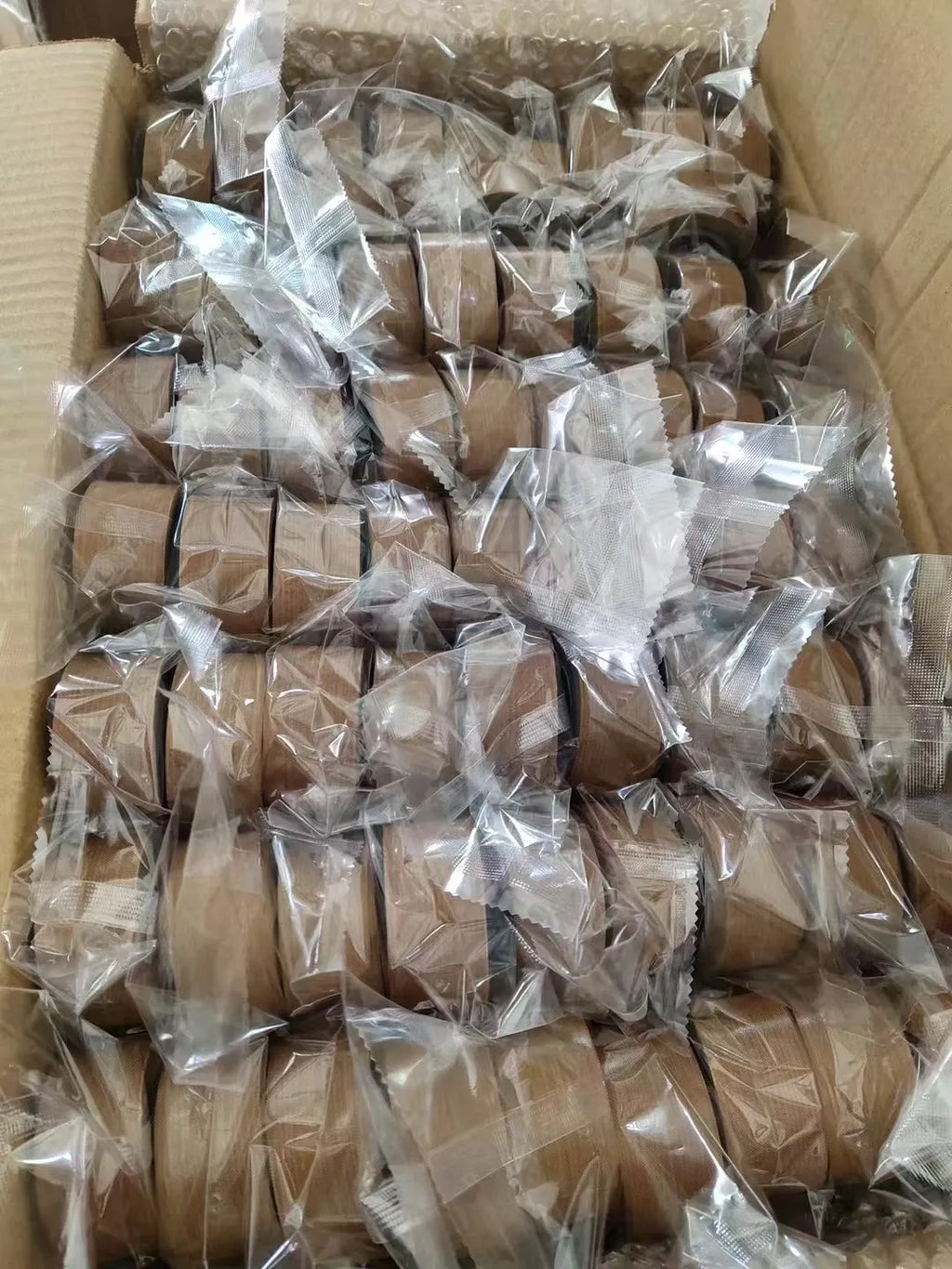 Carton filled with heat-sealing tape rolls, each wrapped in clear plastic