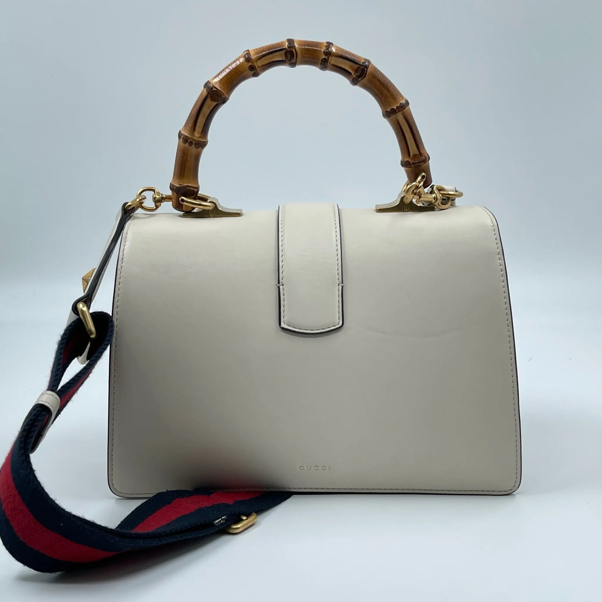 White genuine leather Gucci designer handbag with bamboo top handle and colorful striped detachable shoulder strap.