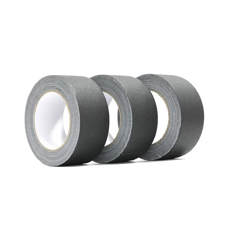Multiple rolls of black matte gaffer tape stacked, showing gray inner cores