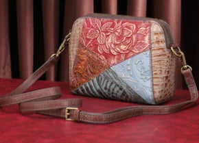 Designer leather crossbody bag with multi-color floral patchwork and embossed textured panels.