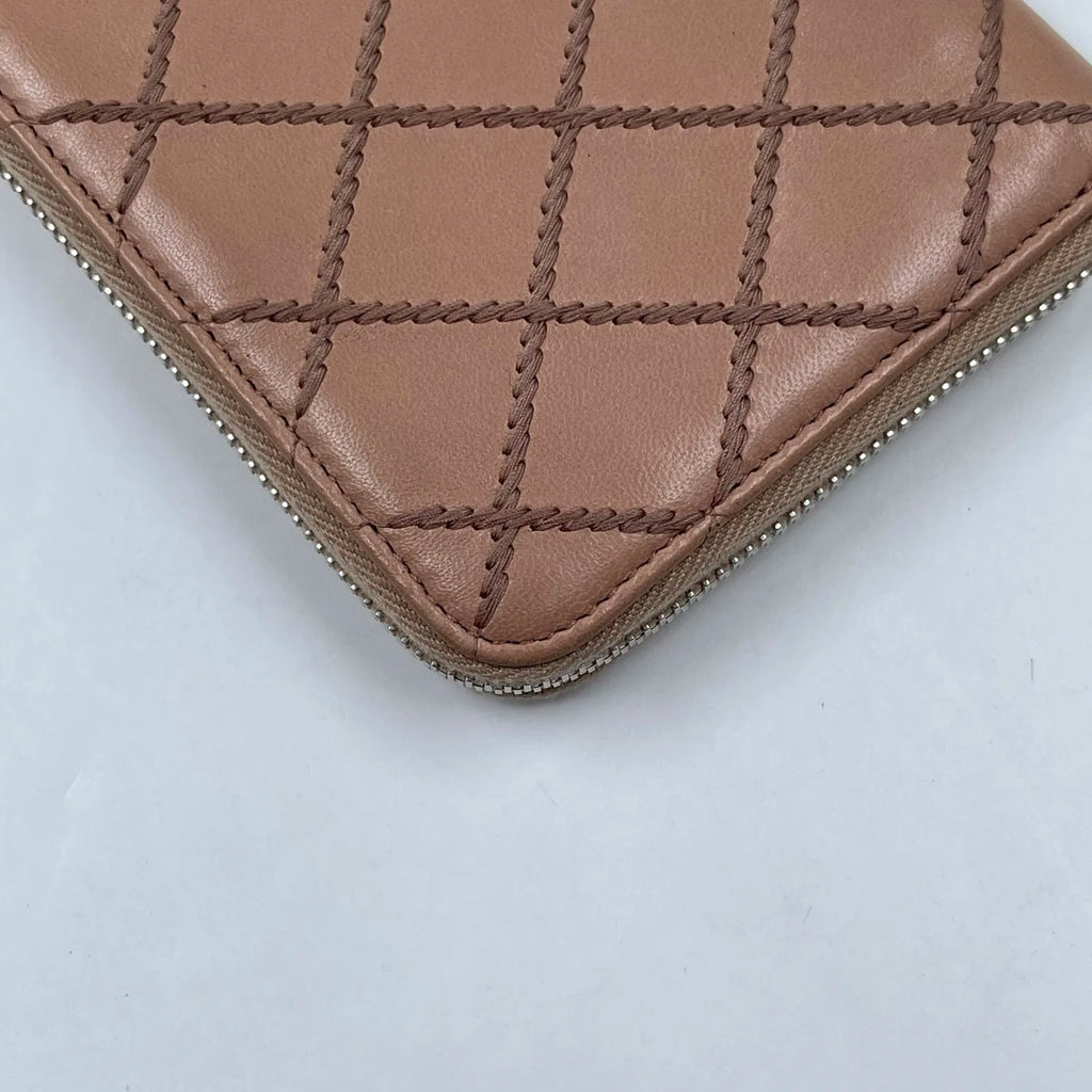 Dusty rose quilted genuine leather designer wallet with zip-around closure and grid stitching. Designer handbags.