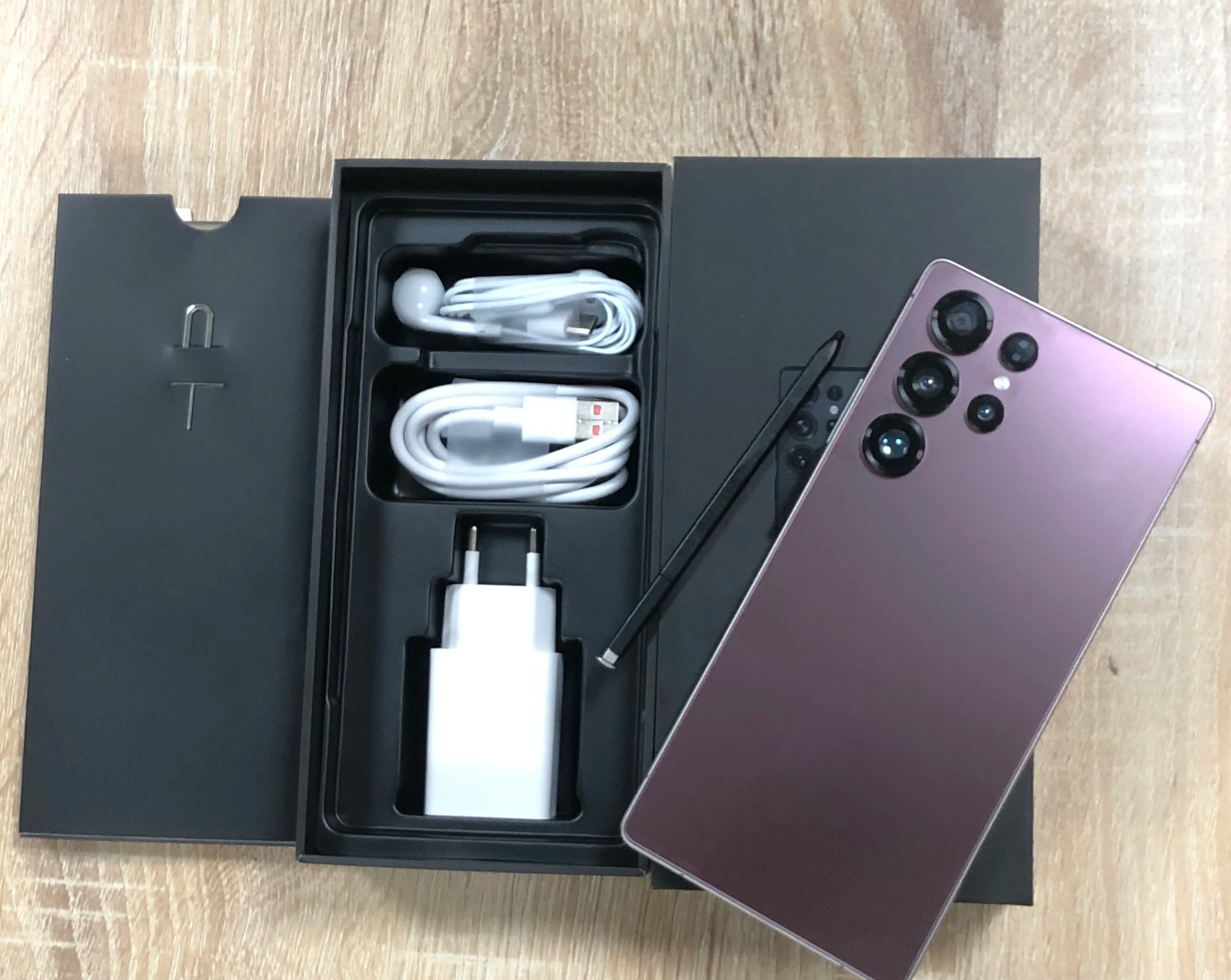 Android smartphone with purple back and quad rear cameras; box with cable and charger