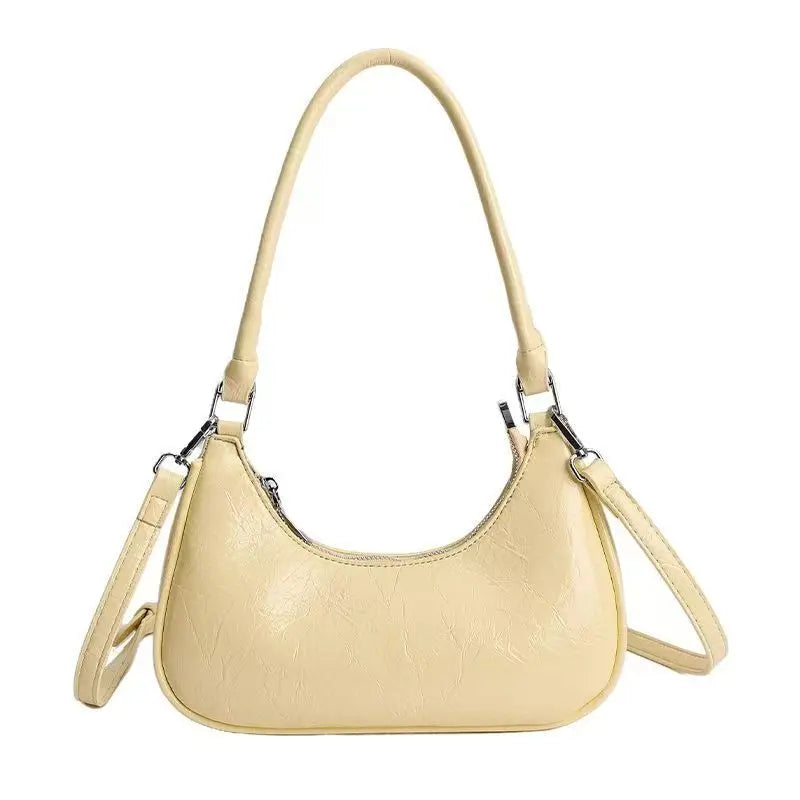 Cream textured leather dumpling bag with shoulder strap, silver hardware, and versatile crossbody design.