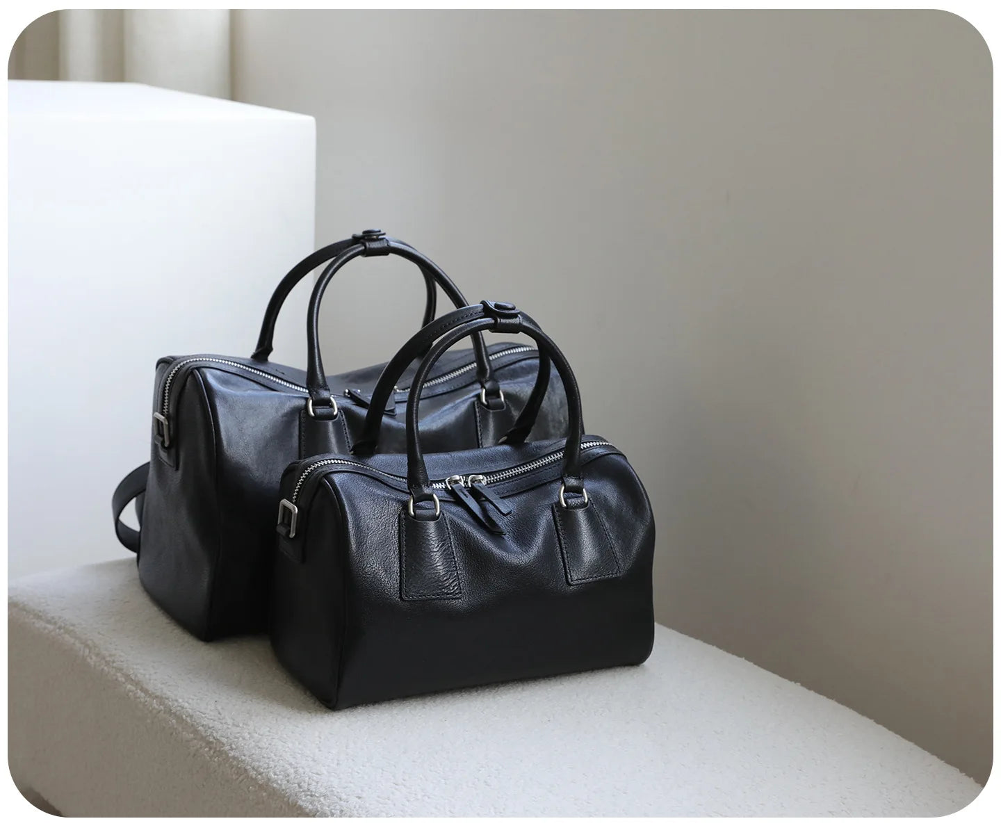 Black vegetable-tanned leather Boston bags with double zippers, minimalist style for luxury designer handbags.