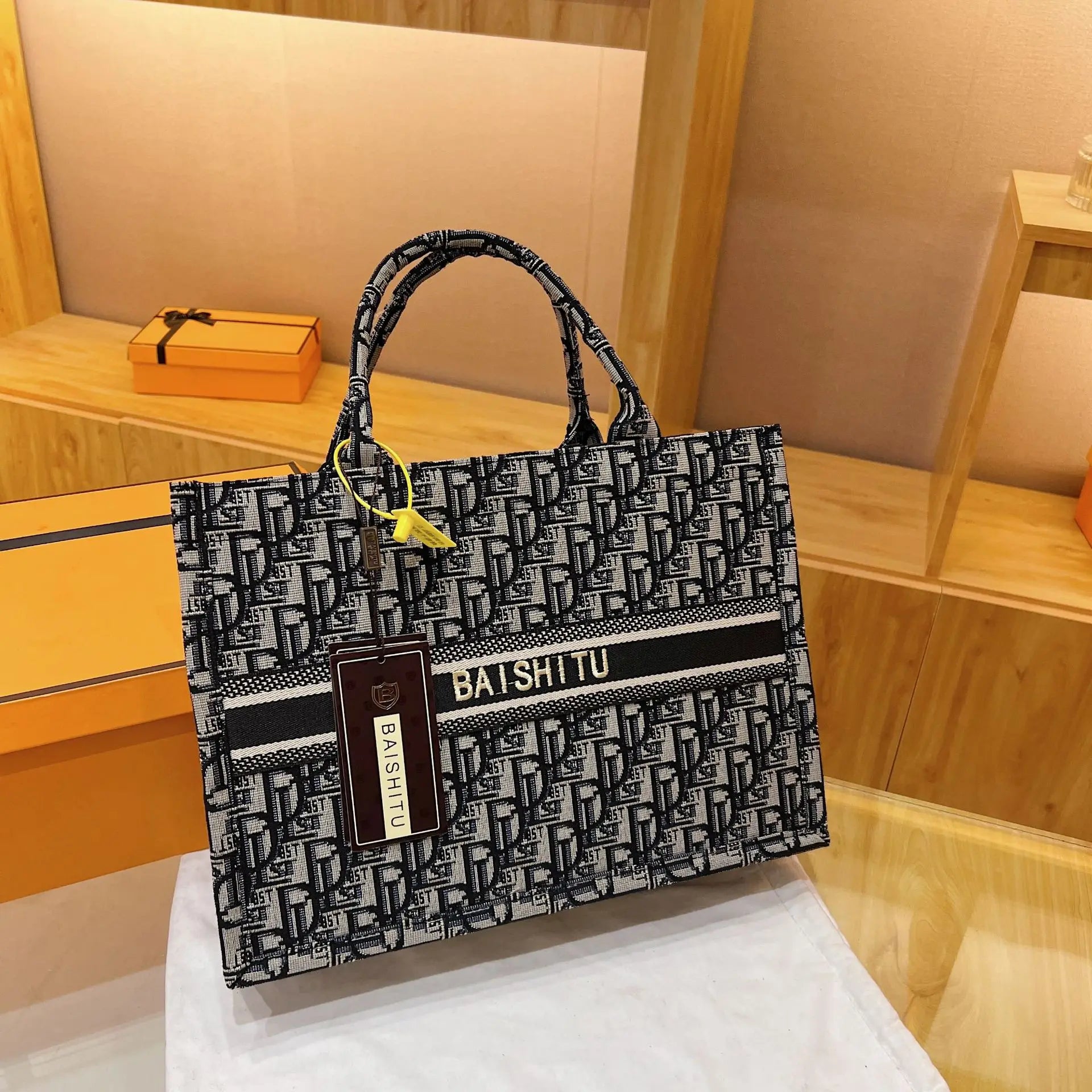 Black and white monogram canvas tote bag with top handles, Baishitu logo stripe, and structured square trunk style.