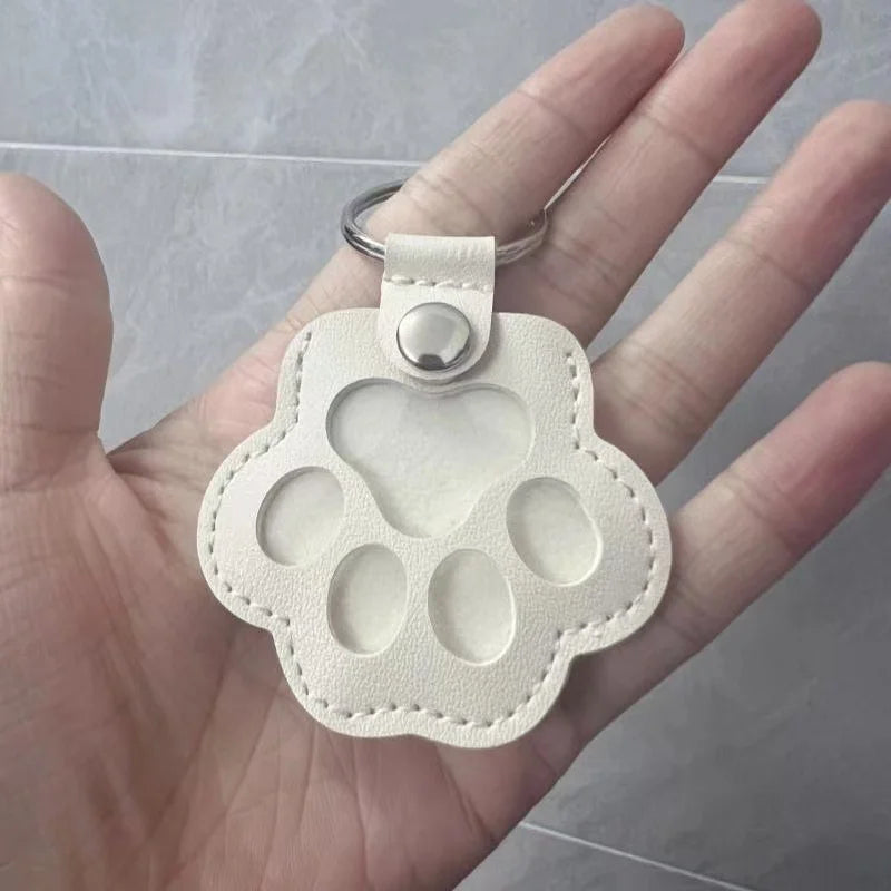 White leather cat paw keychain storage bag to carry pet hair as a memorial keepsake or portable pet charm.