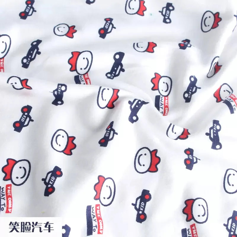 Tidesmit white knit jersey fabric featuring a repeating pattern of cartoon smiley faces and small navy blue toy cars.