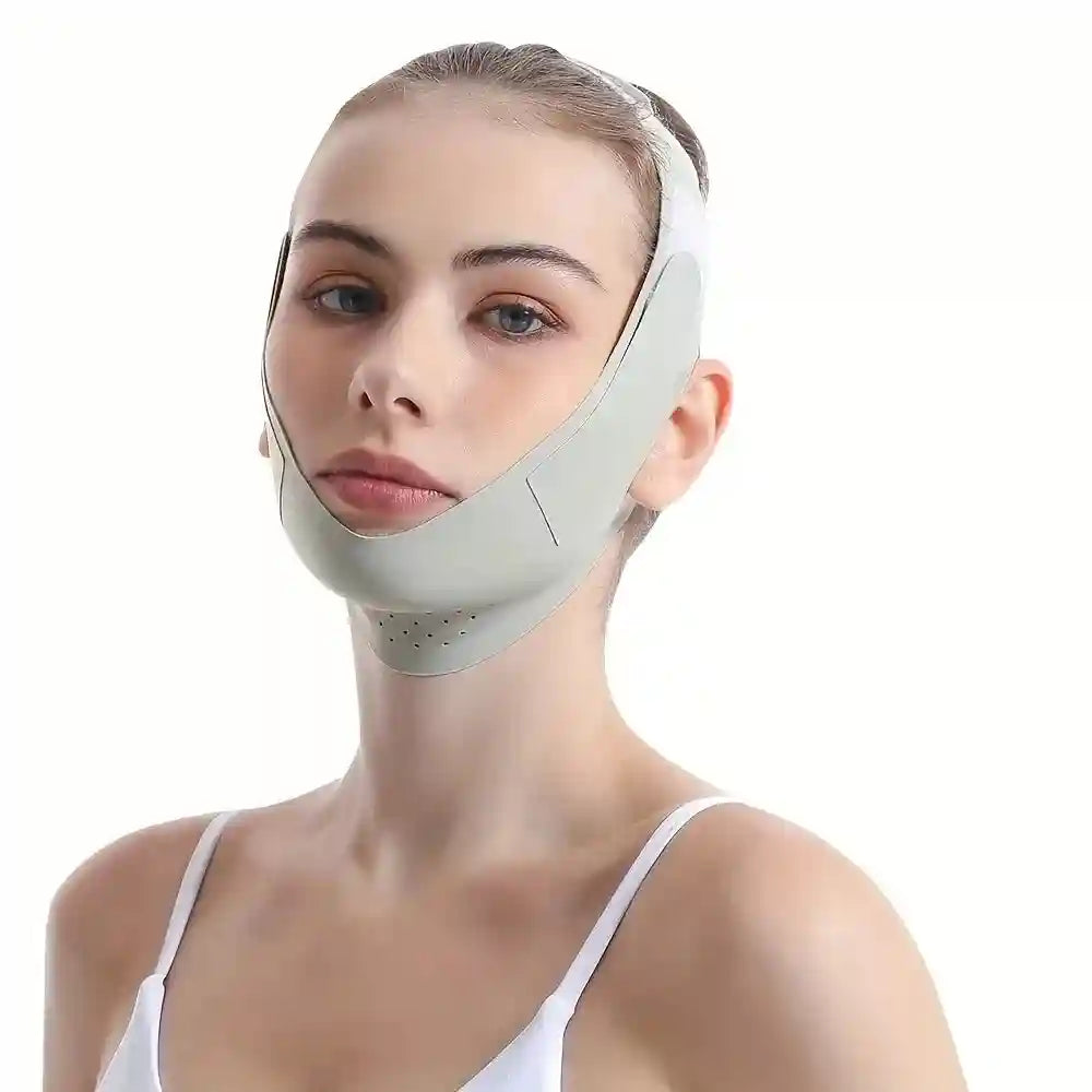 Woman wearing a light gray, perforated V-line face slimming bandage strap under her chin against a white background.
