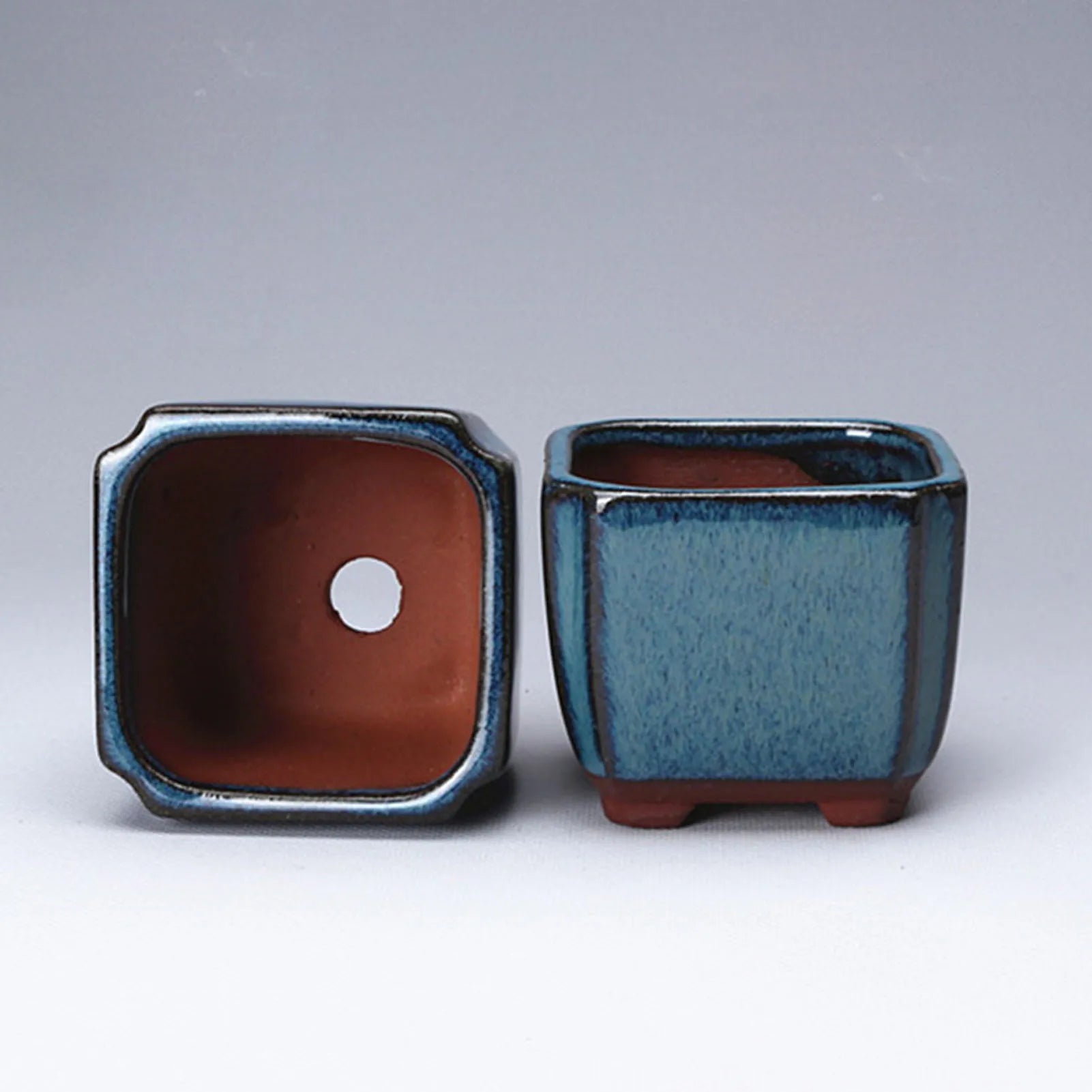 Blue glazed ceramic pot bottom view with terracotta interior and vent hole