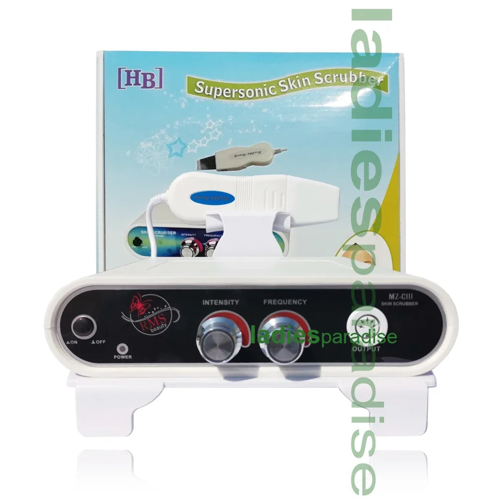 Supersonic skin scrubber device with white plastic control unit, two adjustment dials, and handheld facial spatula.
