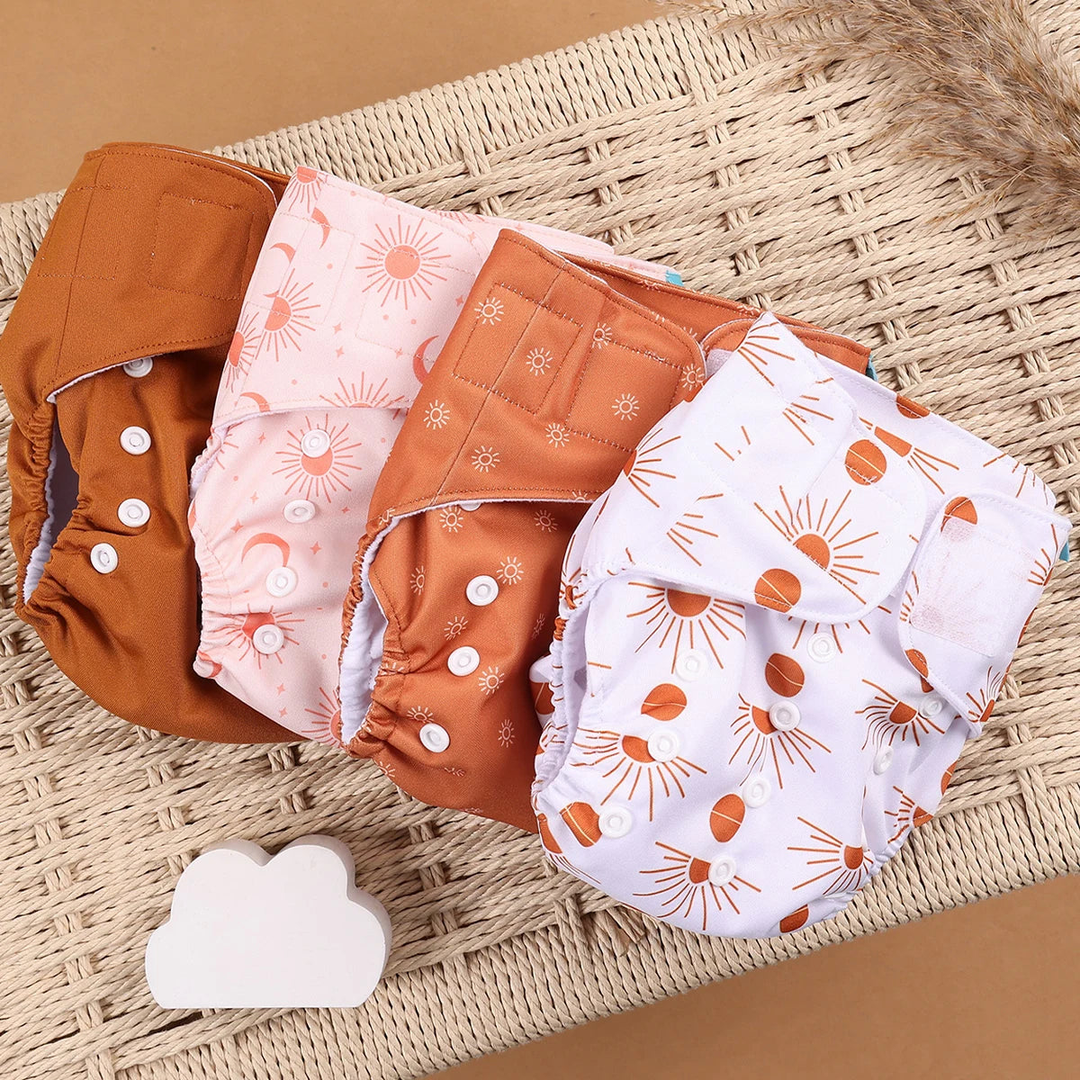 Reusable cloth diapers with boho sun and moon patterns in earthy tones. Set of four adjustable baby care diapers.