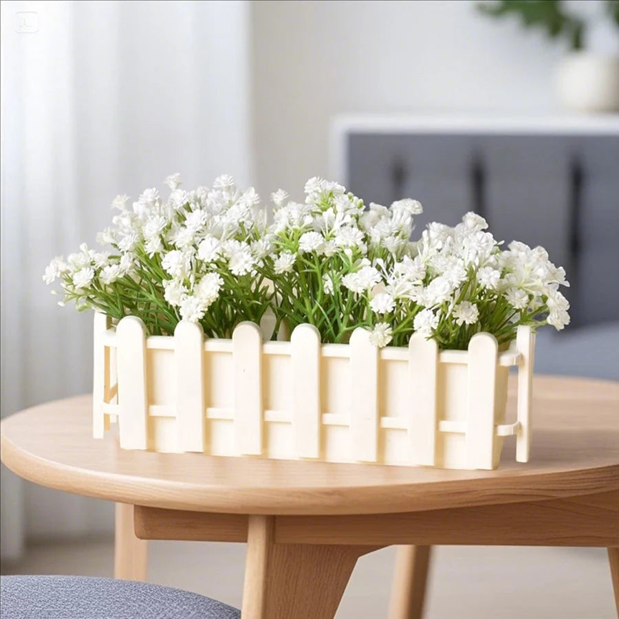 White fence-style rectangular planter pot with white flowers on a round wooden tabletop