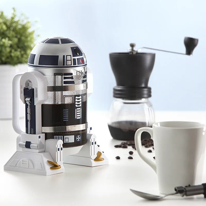 Star Wars R2-D2 glass and plastic French press coffee maker with white and blue droid design on a kitchen table.