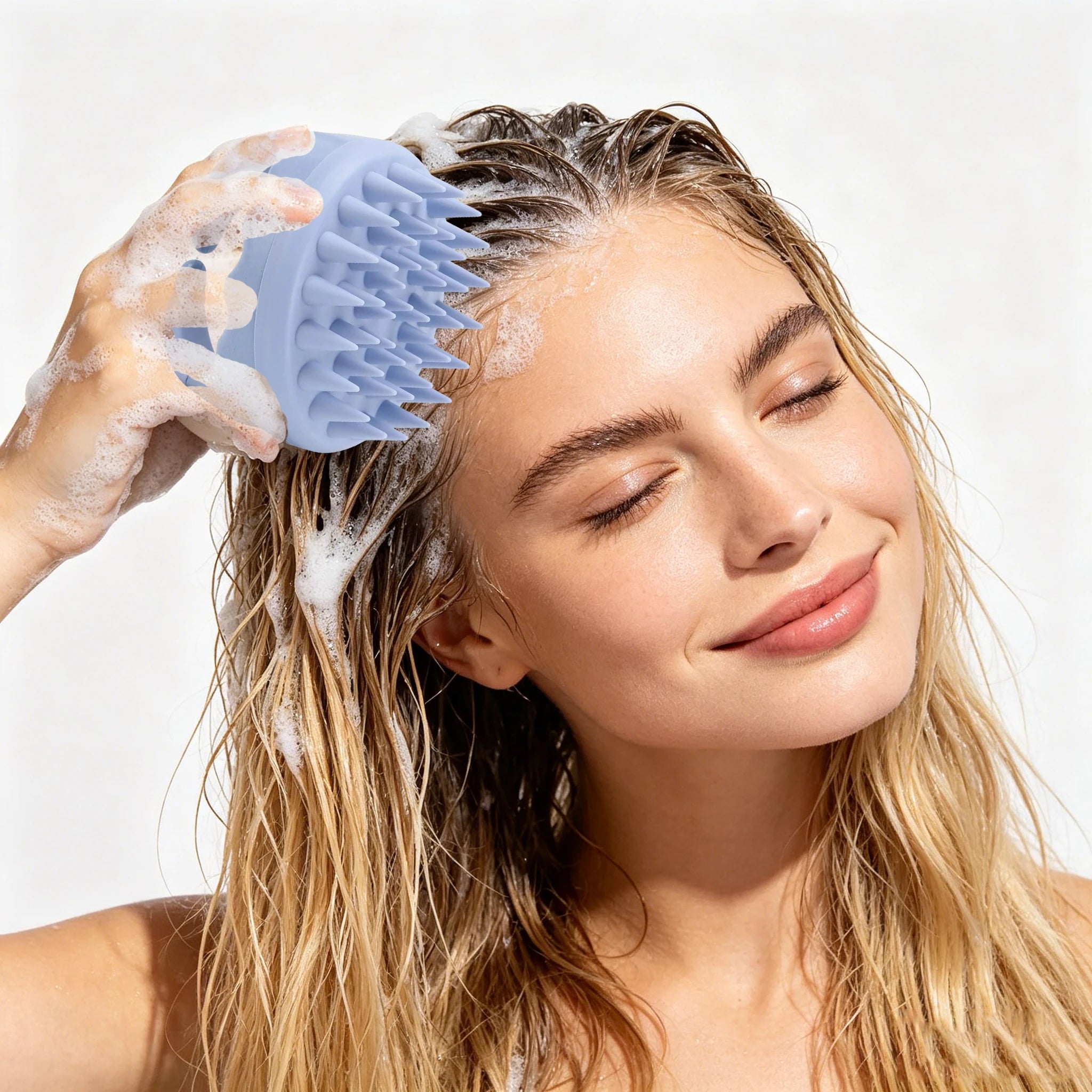 A person using a light blue silicone scalp massager brush to lather suds into their wet hair.