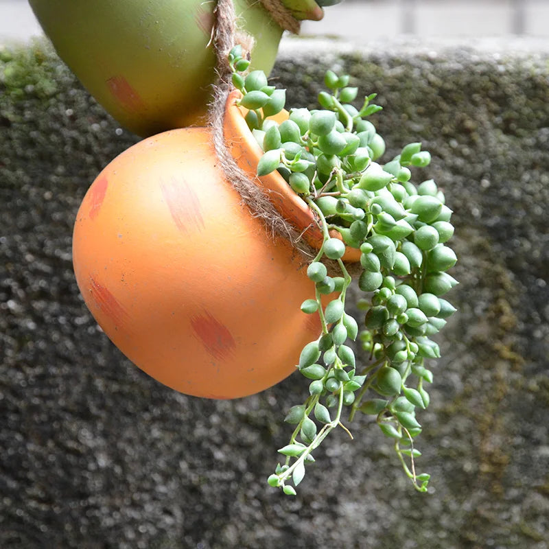 Hanging ceramic flowerpot with orange and green finishes holding a trailing succulent