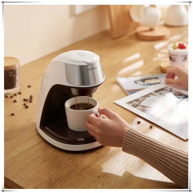 Konka white and brown single-serve coffee maker brewing fresh coffee into a white ceramic cup on a wooden table.