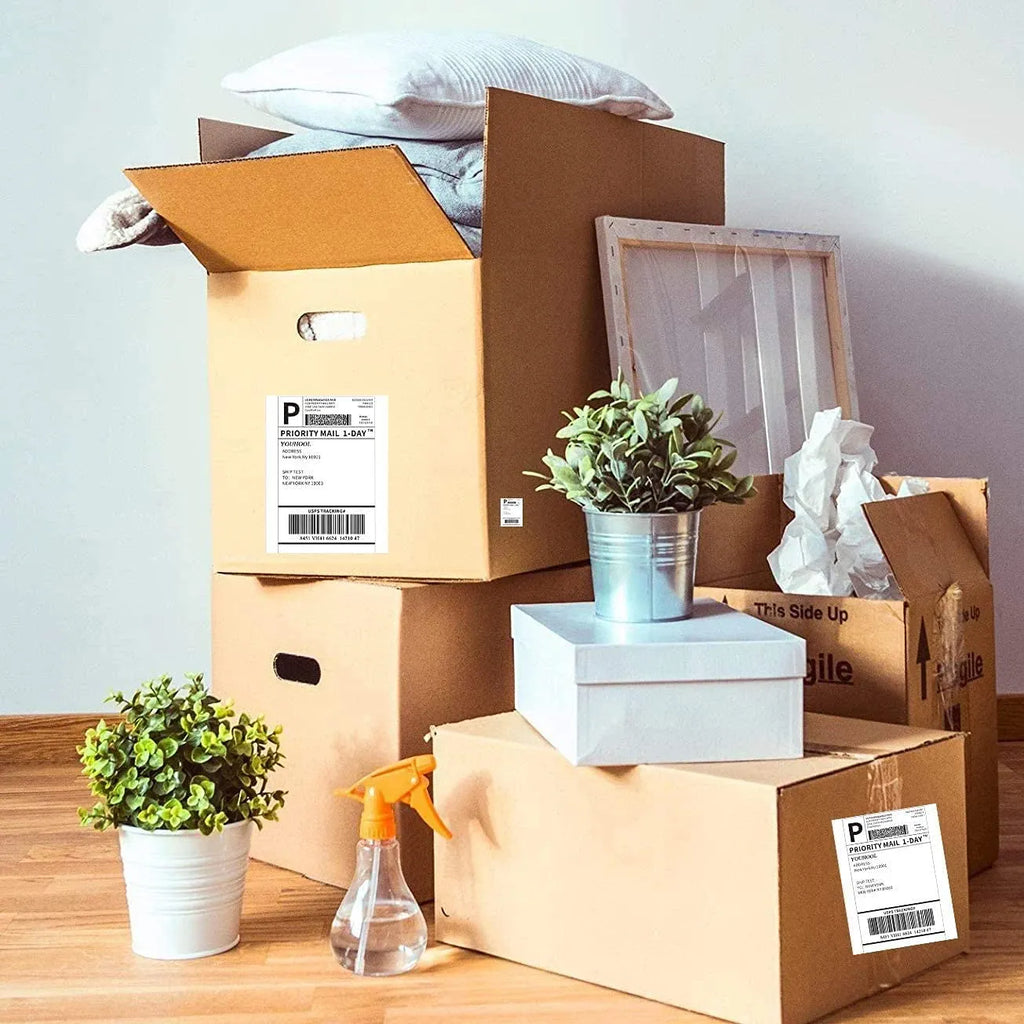 Thermal shipping labels on cardboard moving boxes with barcoded address tags.