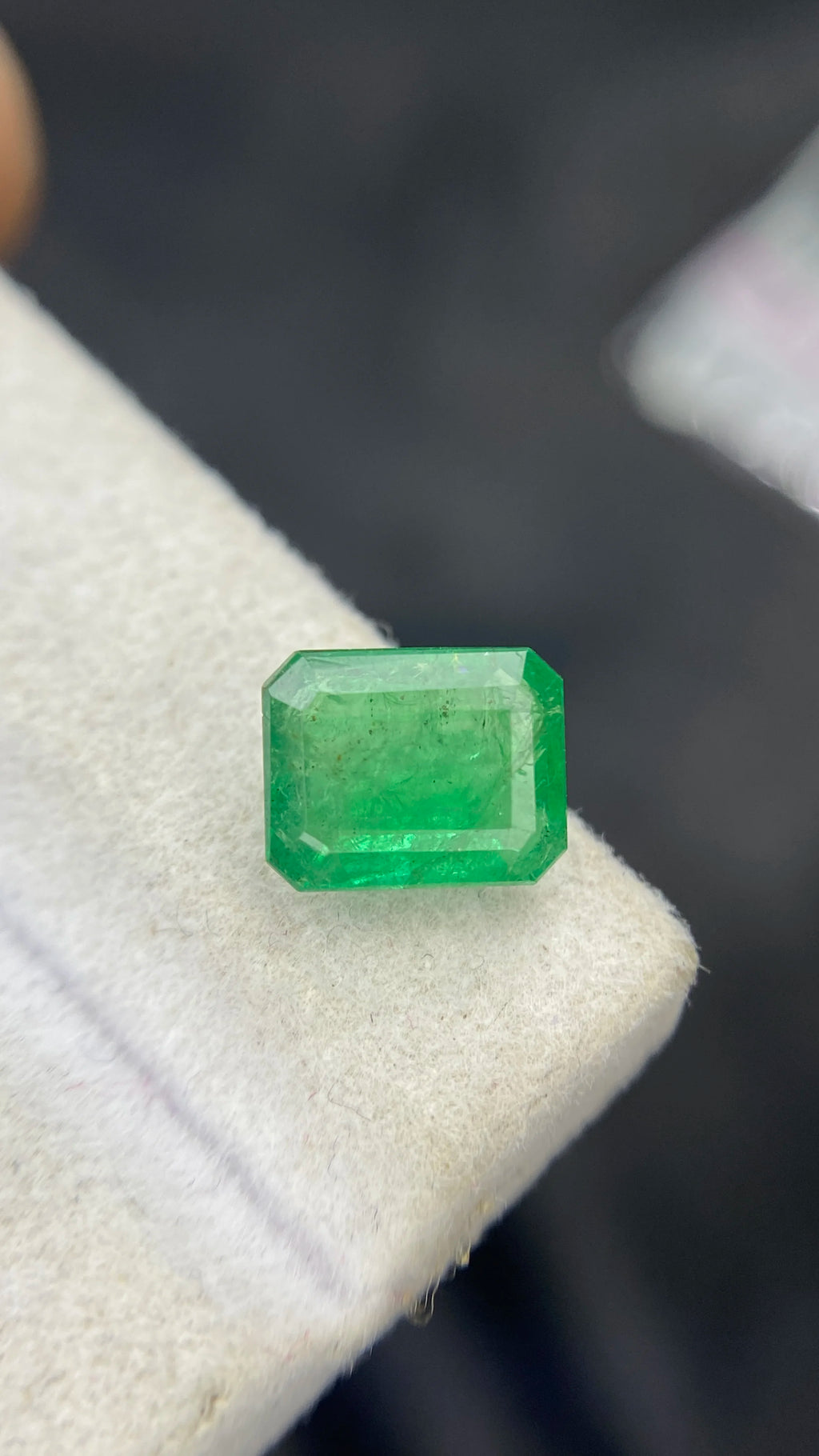 Green octagon emerald-cut gemstone, loose stone resting on white felt