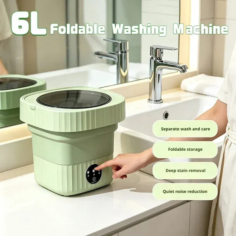 Foldable washing machine in green on a bathroom counter with a hand pressing the power button.