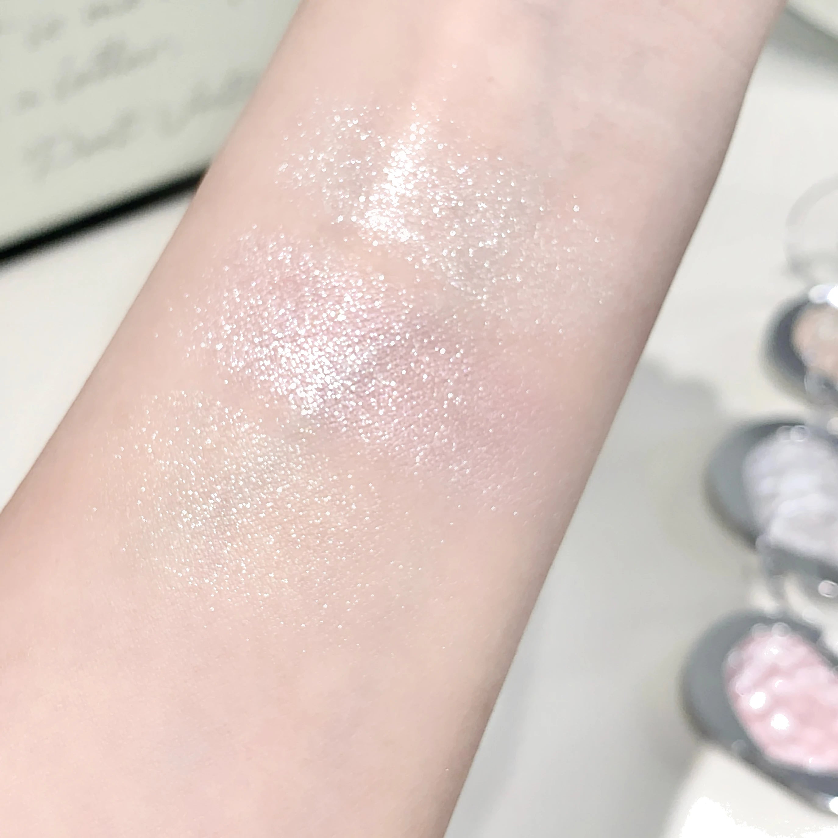 Tidesmit LEE INTO highlighter powder texture close-up featuring fine shimmer and silky pearlescent finish