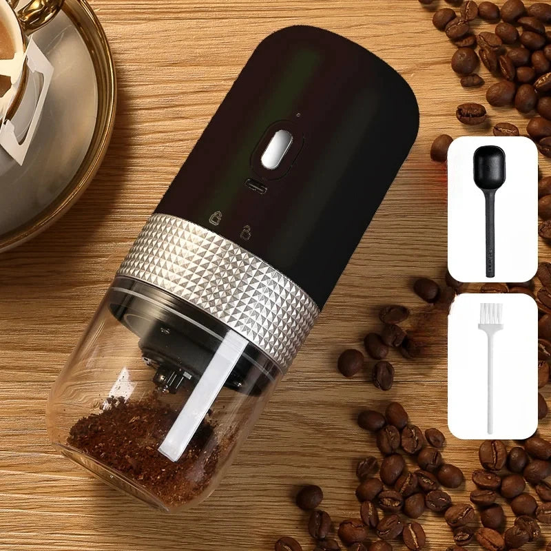 Portable black electric coffee grinder with silver textured grip, clear base, coffee scoop, and cleaning brush.