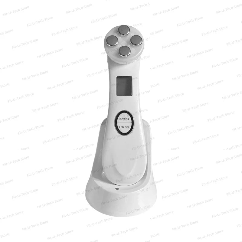 White EMS facial massager with a five-probe head, digital screen, and power buttons, resting in a charging base.