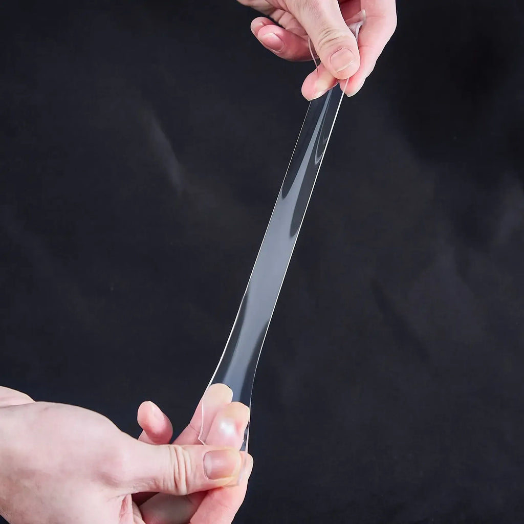 Clear double-sided tape strip being pressed onto a smooth surface for mounting