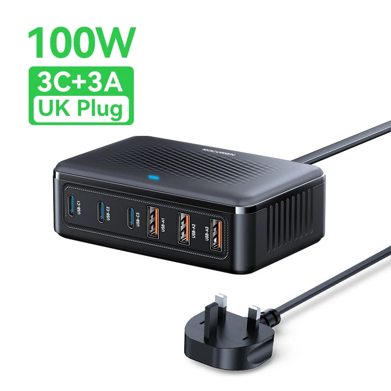 Black rectangular 100W GaN desktop charging station with 6 ports, textured top, LED light, and a UK power plug.