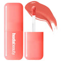 Coral hydrating liquid lip and cheek tint with applicator, showing smooth, creamy texture and vibrant peachy pink color.