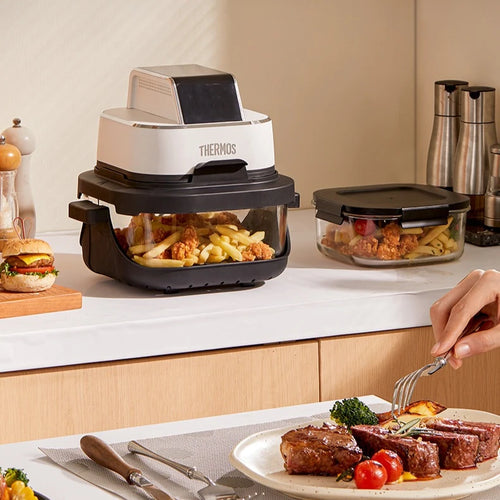 Thermos air fryer on kitchen counter with glass drawer and separate cooking bowls