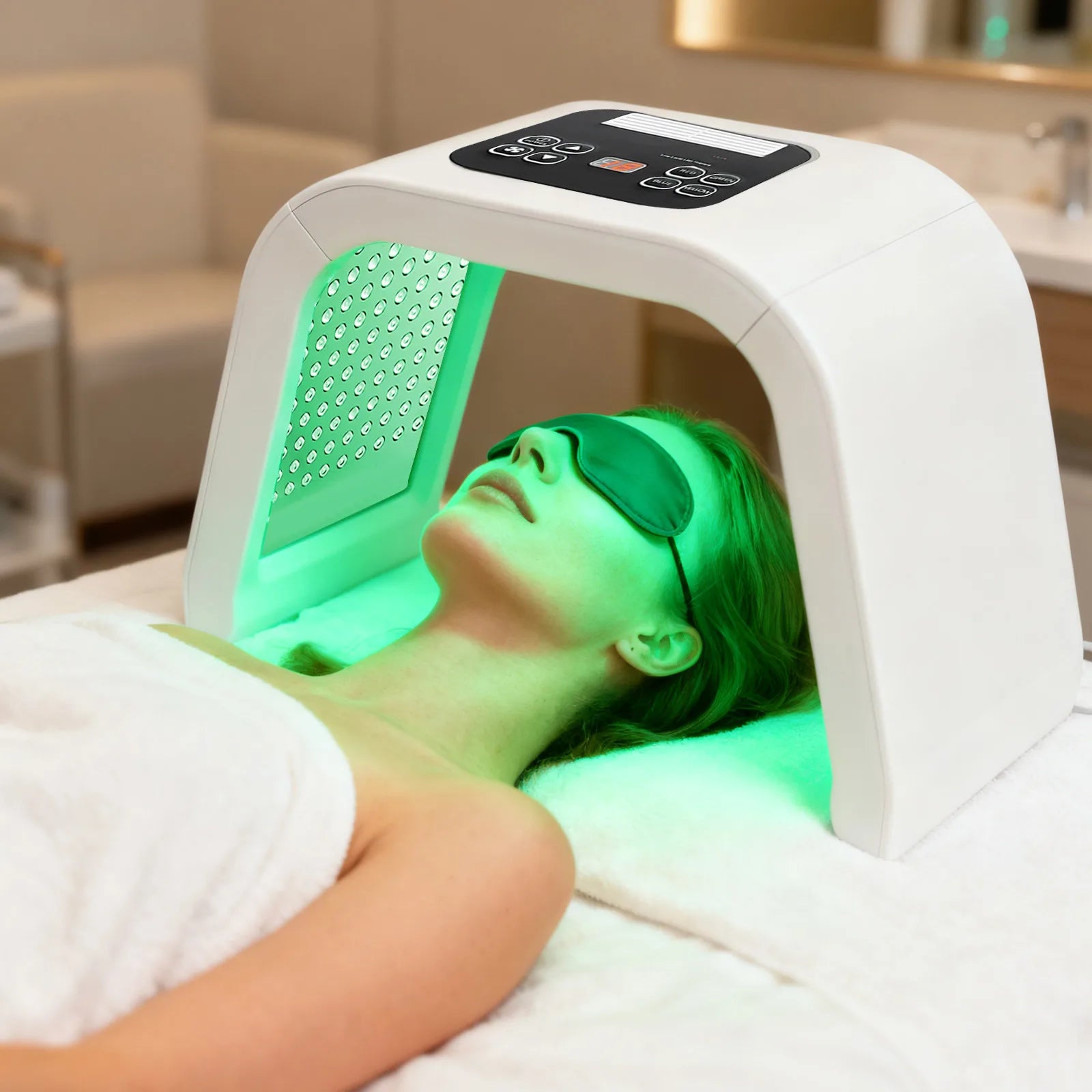 A woman lying on a spa bed under a white arch-shaped LED light therapy machine emitting a bright green glow.