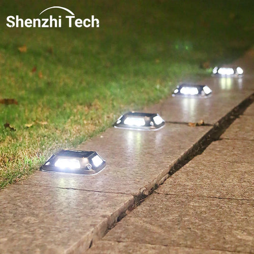 Solar LED driveway lights with dome heads, glowing along a concrete walkway edge