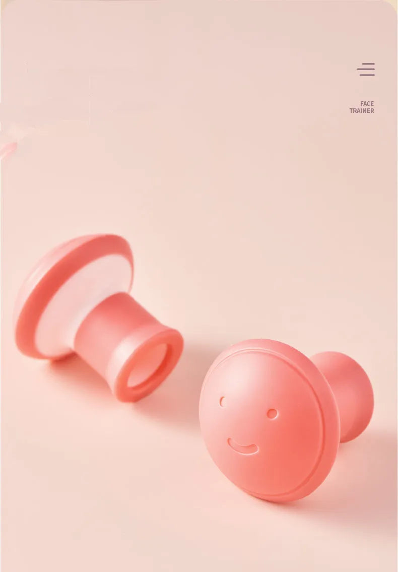 Two pink, mushroom-shaped silicone facial exercisers on a soft pink background; one features a cute smiley face.