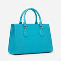 Bright turquoise genuine leather designer handbag with vintage alligator embossed texture and top handles.