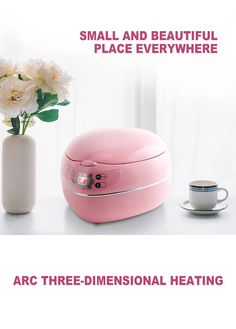 Pink heart-shaped mini rice cooker with closed lid on a clean tabletop setup.