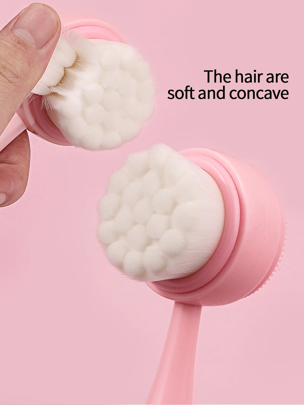 Pink handheld manual facial cleansing brush with soft, concave white bristles for deep pore skincare and makeup removal.