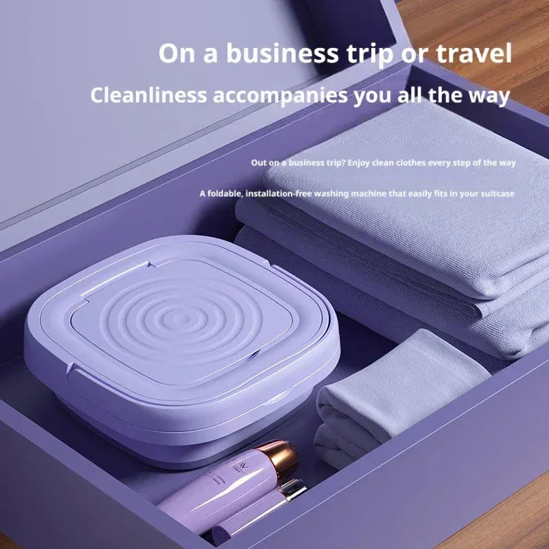 Portable washing machine folded in a purple suitcase with folded clothes for travel.