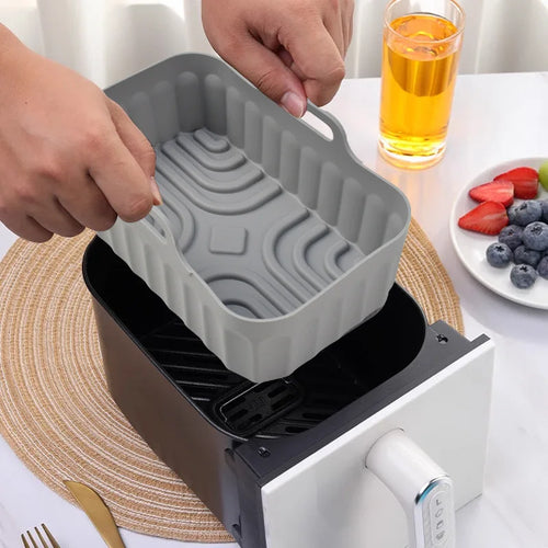 Gray silicone baking mold accessory for air fryer, shown being placed