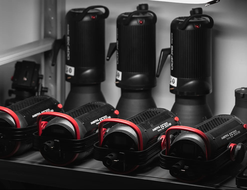 Ambitful EF300 LED video lights with black cylindrical housing and red metal handles, stored on a shelf.