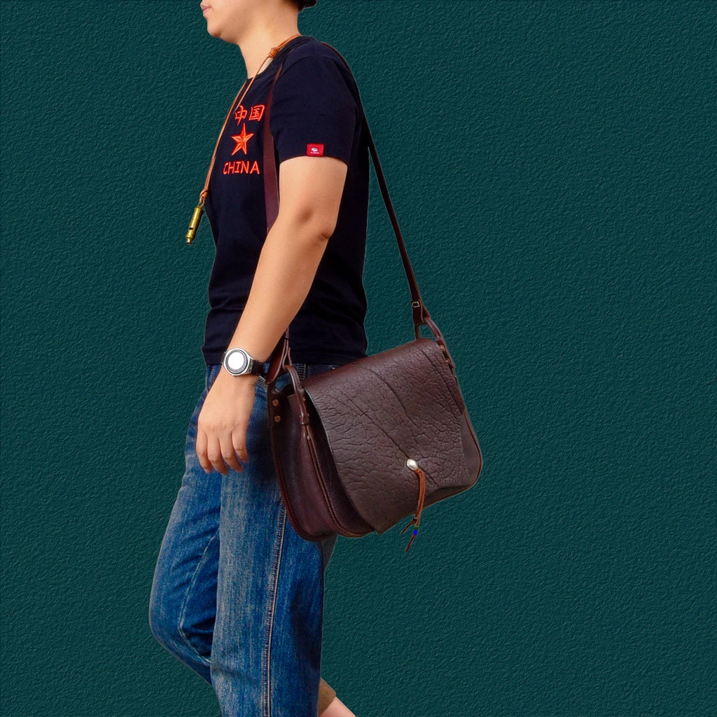 PNDME handmade vintage brown cowhide leather messenger bag with flap closure and adjustable shoulder strap for travel.